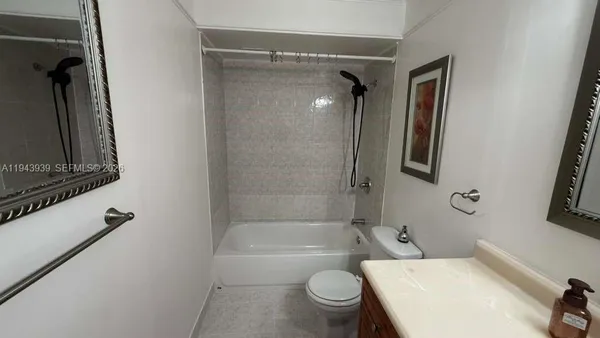 a bathroom with a granite countertop bathtub shower sink vanity and toilet