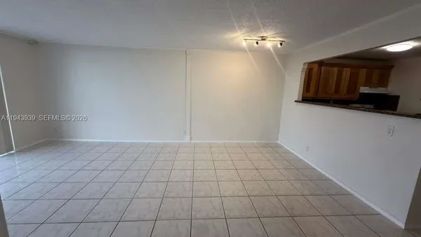 a view of an empty room and kitchen space with window