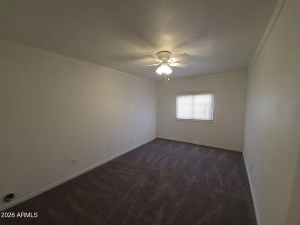 an empty room with a window and a fan