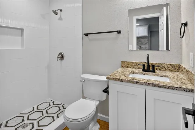 a bathroom with a granite countertop toilet sink and mirror