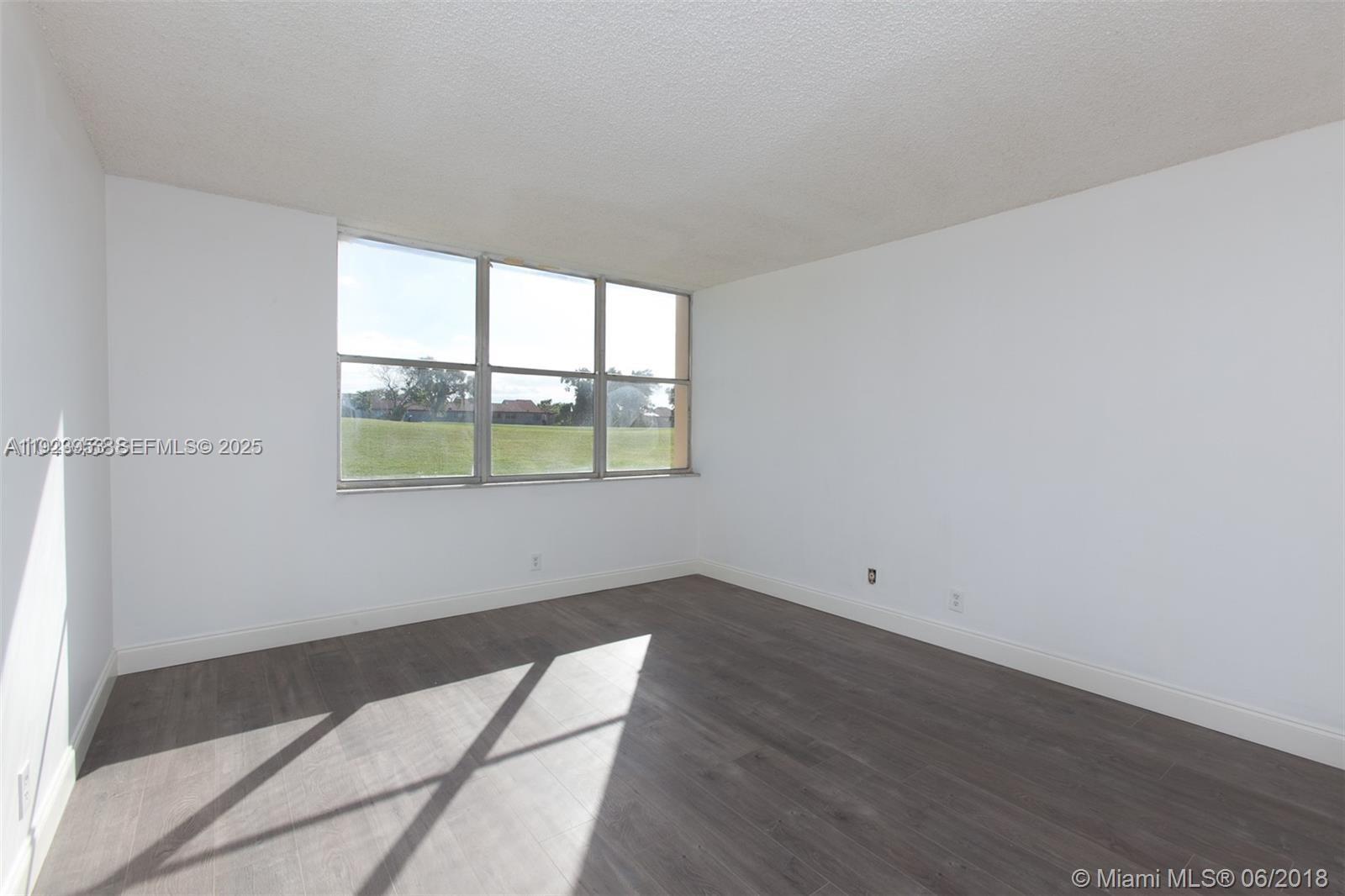 3821 Environ Boulevard, Unit 107 Lauderhill, FL 33319 - Photo 8 of 19 an empty room with wooden floor and windows