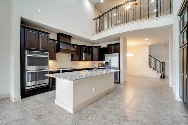 a open kitchen with stainless steel appliances kitchen island granite countertop a refrigerator and a sink