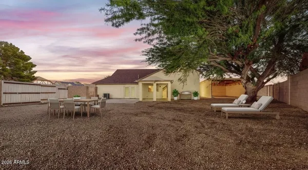 a view of a house with a chairs and table in the backyard