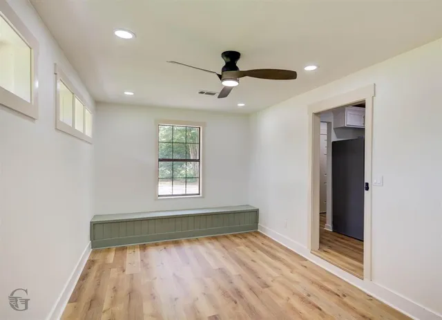 a view of empty room with wooden floor and fan