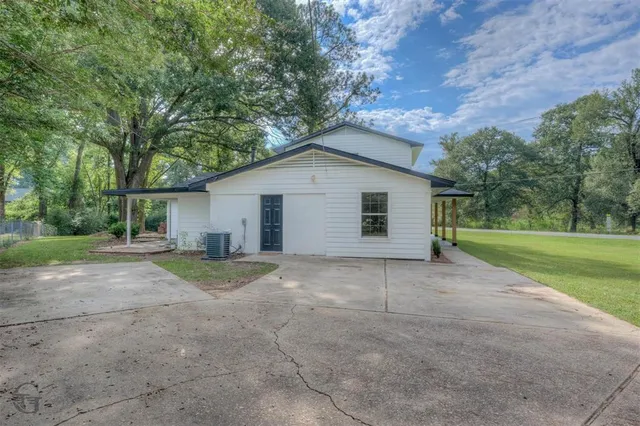 a view of a house with a yard and large trees