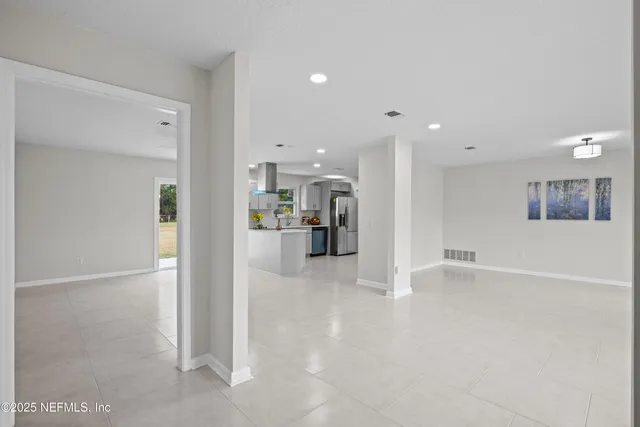 a view of an empty room with wooden floor and window