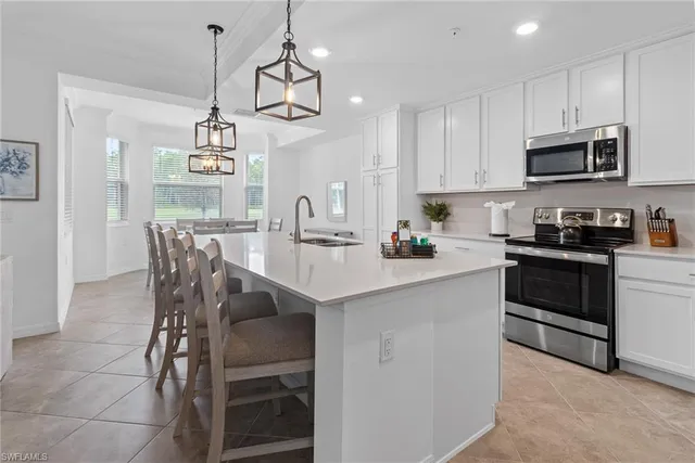 a kitchen with stainless steel appliances kitchen island granite countertop a stove and white cabinets