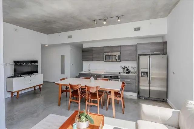 a kitchen with stainless steel appliances a stove a refrigerator and a dining table