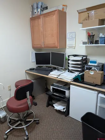 a view of a workspace with furniture and a window