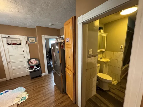 a view of a hallway with wooden floor and a bathroom