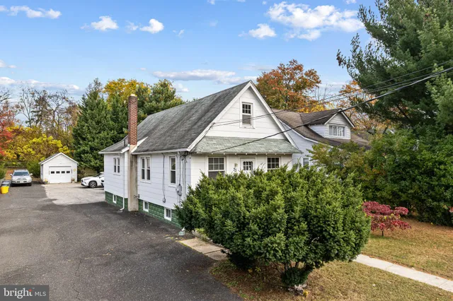 a view of a white house next to a road and a yard