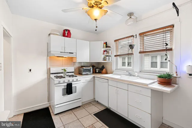 a kitchen with a sink dishwasher a stove and white cabinets