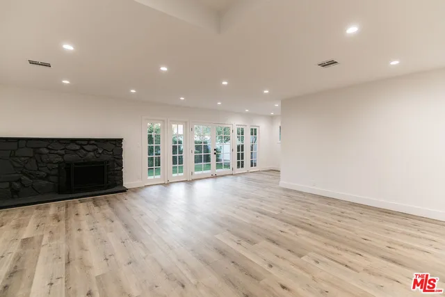 a view of an empty room with wooden floor and a fireplace