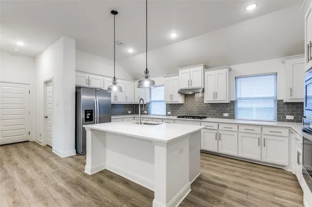 a kitchen with stainless steel appliances sink stove refrigerator and cabinets
