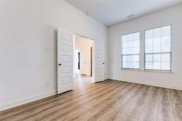 an empty room with wooden floor and windows