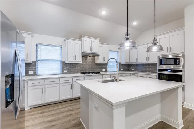 a kitchen with stainless steel appliances a stove a sink a microwave a center island and cabinets