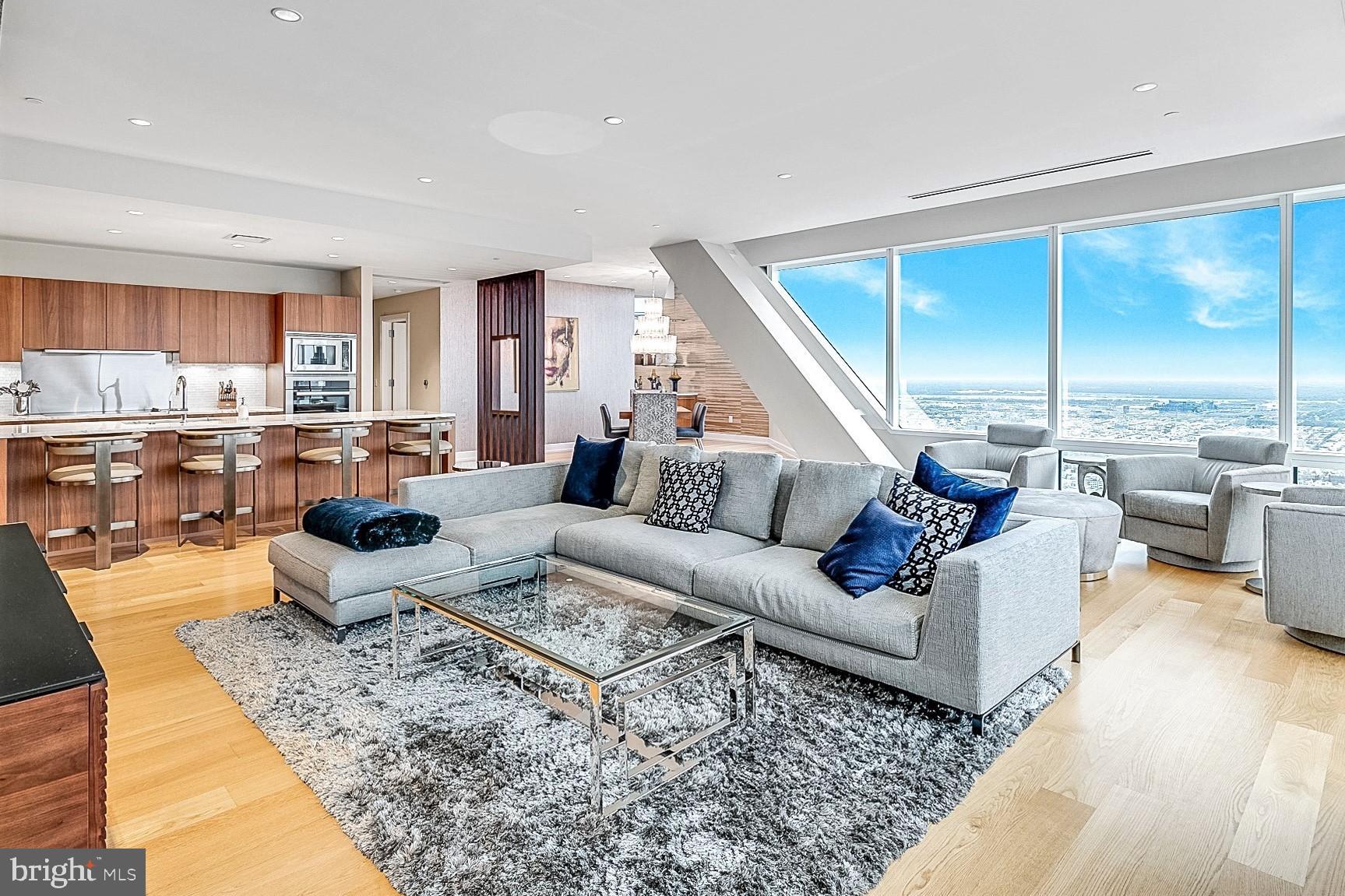 a living room with furniture kitchen view and large windows