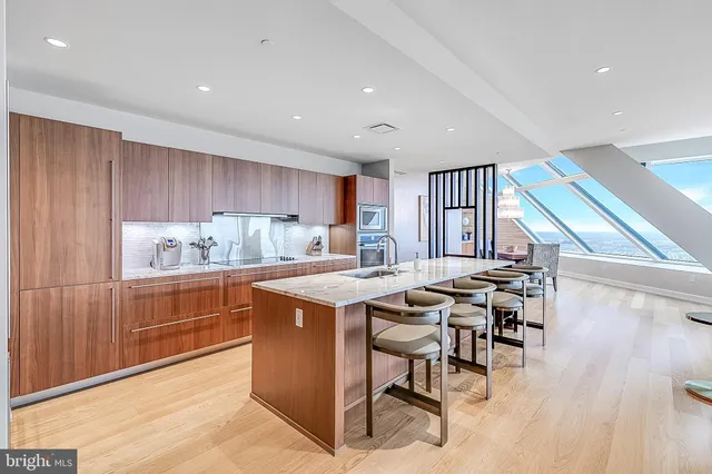 a kitchen with stainless steel appliances granite countertop a table chairs sink and cabinets