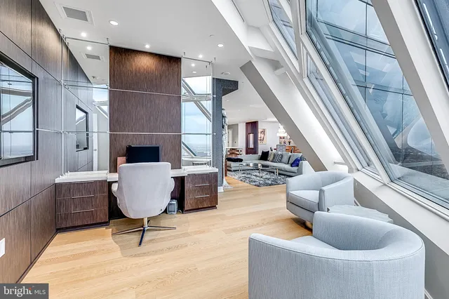 a living room with couches and kitchen view with wooden floor