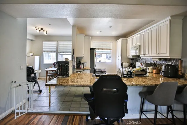 a large dining hall with stainless steel appliances granite countertop a stove a sink a dining table and chairs with wooden floor