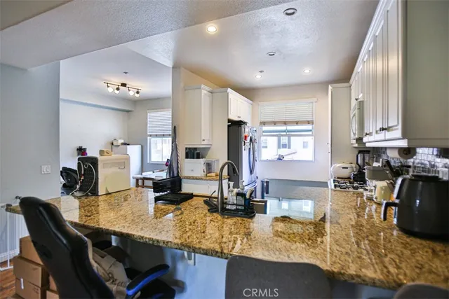 a kitchen with a dining table chairs sink and white cabinets