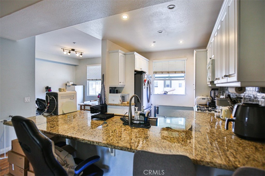 8796 Aspenglow Place, Unit 2 Santee, CA 92071 - Photo 15 of 41 a kitchen with a dining table chairs sink and white cabinets