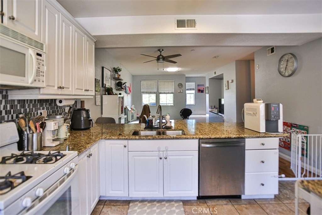 8796 Aspenglow Place, Unit 2 Santee, CA 92071 - Photo 18 of 41 a kitchen with kitchen island granite countertop a sink cabinets and stainless steel appliances