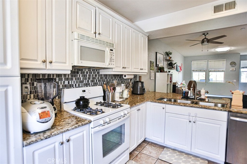 8796 Aspenglow Place, Unit 2 Santee, CA 92071 - Photo 19 of 41 a kitchen with kitchen island granite countertop a sink a stove and cabinets