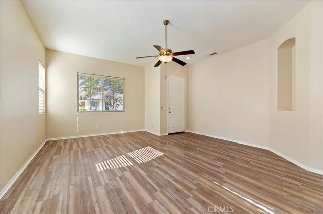 a view of empty room with wooden floor and fan