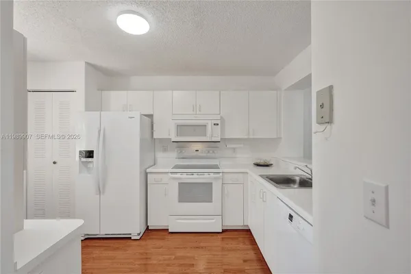 a kitchen with white cabinets and white appliances