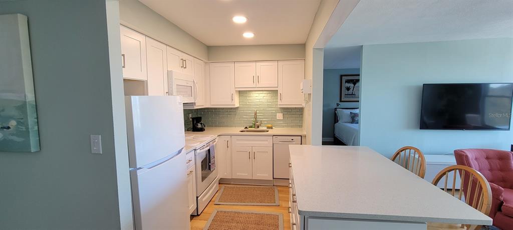 632 Edgewater Drive, Unit 537 Dunedin, FL 34698 - Photo 16 of 28 a kitchen with a refrigerator a stove and a microwave with wooden floor