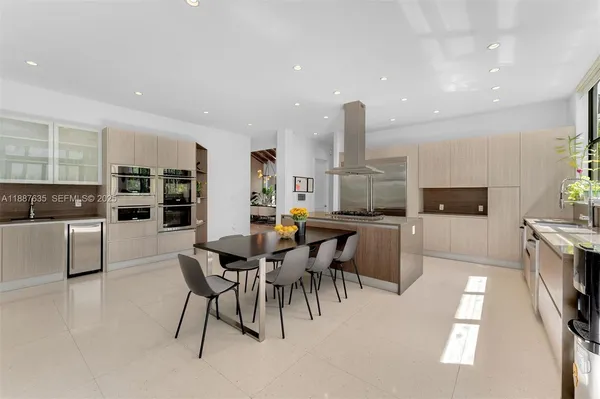 a dining hall with stainless steel appliances kitchen island a table and chairs
