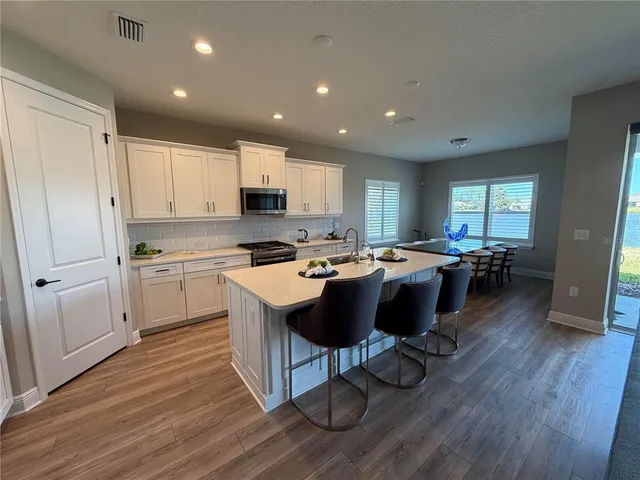 a kitchen with a sink dishwasher a stove a refrigerator and cabinets with wooden floor