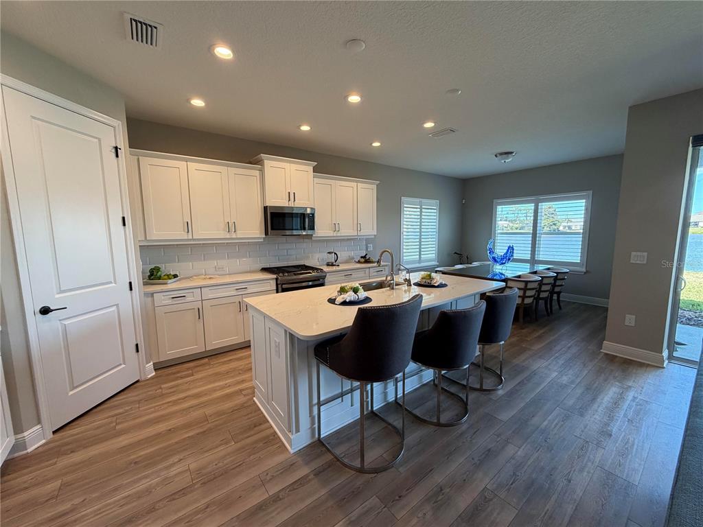 10710 Falling Leaf Court Parrish, FL 34219 - Photo 8 of 28 a kitchen with a sink dishwasher a stove a refrigerator and cabinets with wooden floor