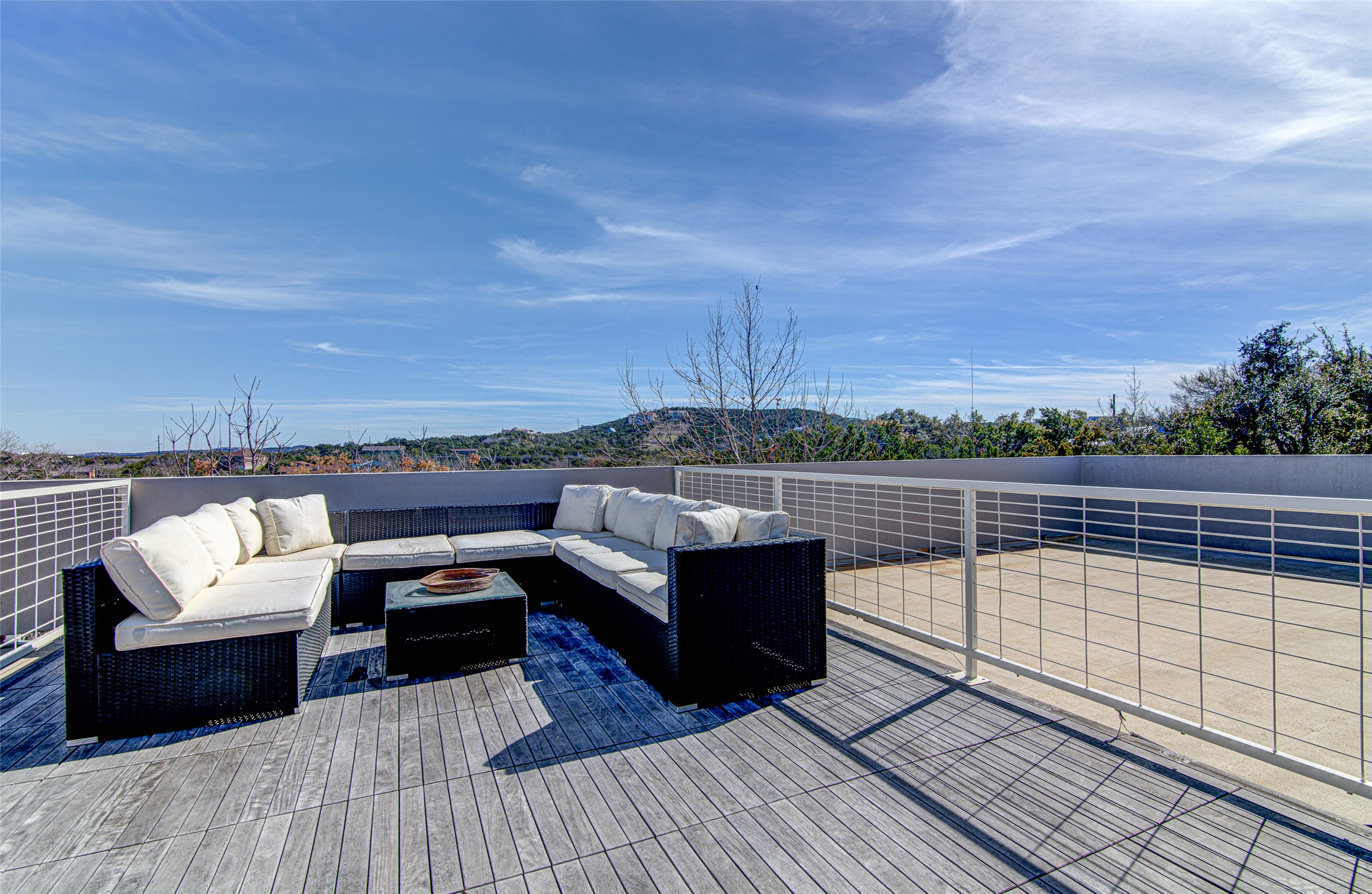 9707 Timber Ridge Pass Austin, TX 78733 - Photo 13 of 18 Panoramic hill country views unfold from this spacious rooftop deck featuring modern horizontal metal railings.