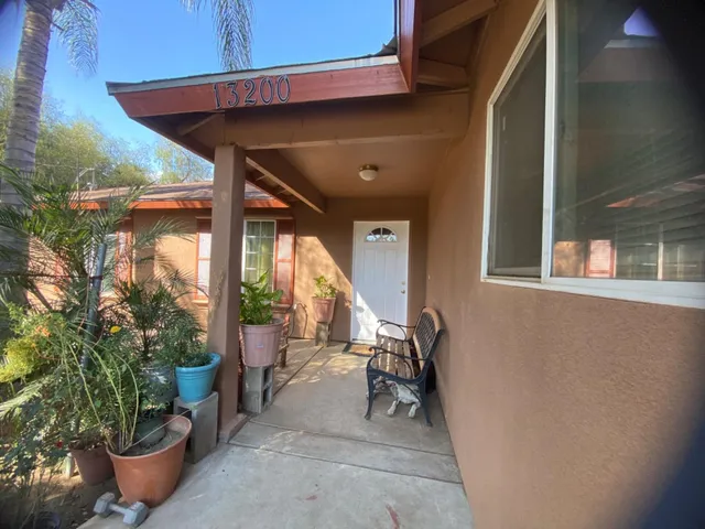 a view of a patio with table and chairs potted plants and floor to ceiling window