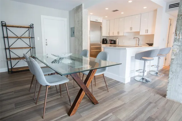 a kitchen with stainless steel appliances kitchen island granite countertop a dining table chairs and granite counter tops