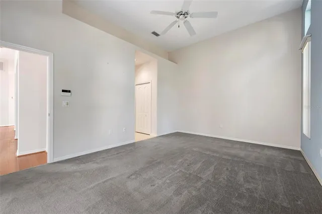 a view of a big room with windows and chandelier fan