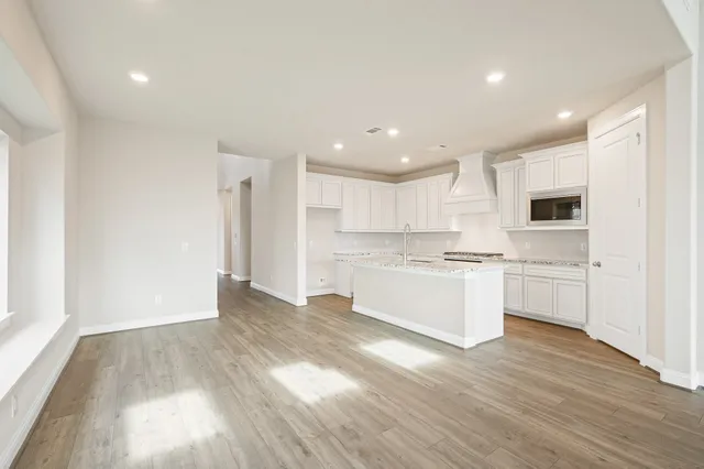 a large white kitchen with a white stove top oven and white cabinets