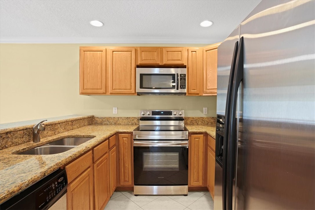 1845 Robalo Drive, Unit 201D Vero Beach, FL 32960 - Photo 11 of 35 a kitchen with granite countertop a stove top oven microwave and refrigerator
