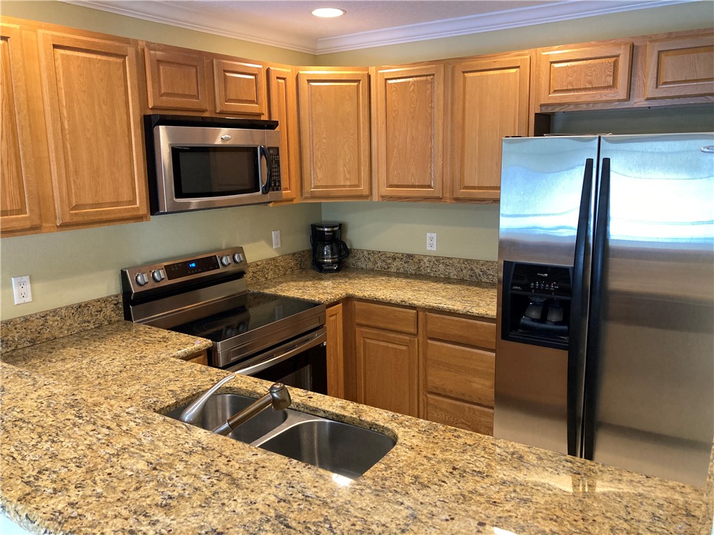 1845 Robalo Drive, Unit 201D Vero Beach, FL 32960 - Photo 8 of 35 a kitchen with stainless steel appliances granite countertop a refrigerator sink and stove