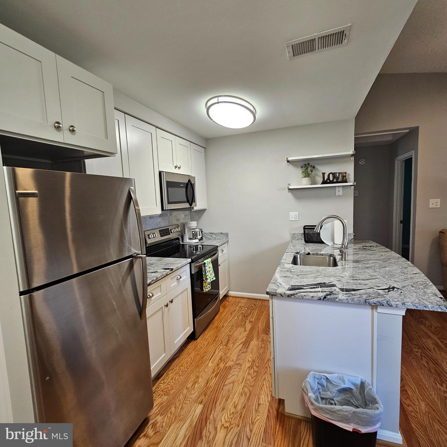 8637 D Beekman Place, Unit 37D Alexandria, VA 22309 - Photo 6 of 18 a kitchen with granite countertop stainless steel appliances a refrigerator a stove a sink and a refrigerator
