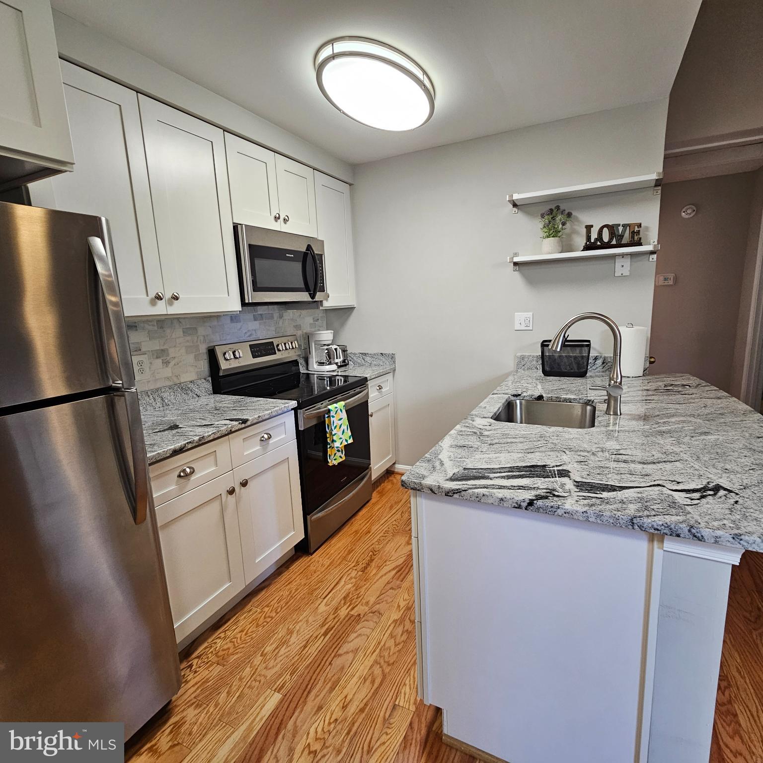 8637 D Beekman Place, Unit 37D Alexandria, VA 22309 - Photo 9 of 18 a kitchen with stainless steel appliances granite countertop a sink stove microwave and refrigerator