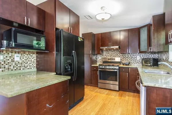 a kitchen with stainless steel appliances granite countertop a refrigerator a stove and a sink