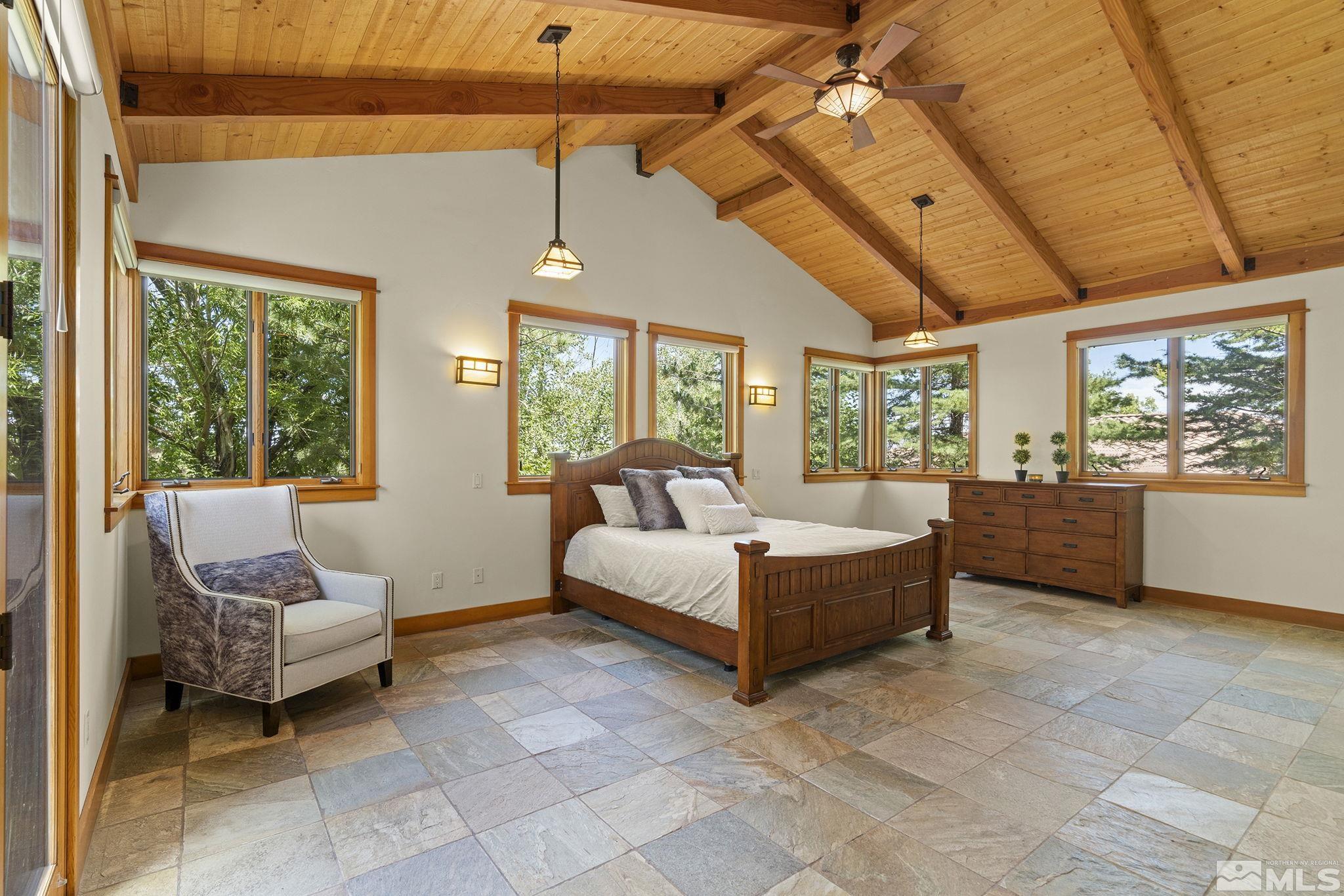 7035 Quail Rock Lane Reno, NV 89511 - Photo 16 of 37 a spacious bedroom with a bed a flat screen tv and balcony view