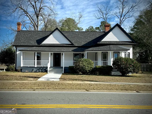 a front view of a house with a yard and potted plants