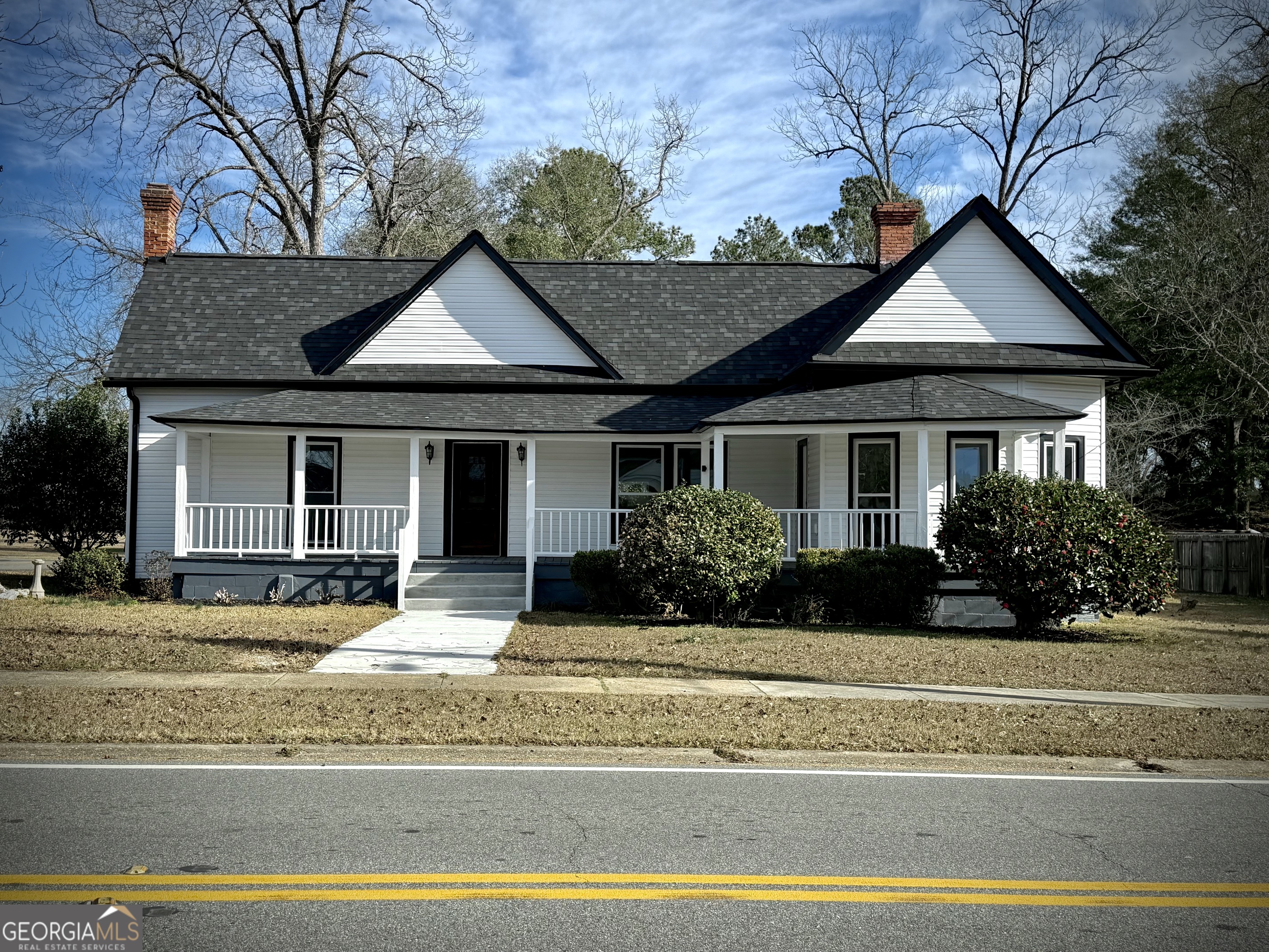 a front view of a house with a yard and potted plants