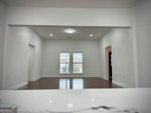 an empty room with wooden floor chandelier fan and windows