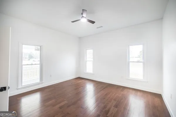 a view of an empty room with wooden floor and window