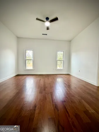 an empty room with wooden floor fireplace and windows